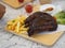 Pork Spareribs BBQ, Barbeque Pork Ribs with french fries vegetable salad, tomato sauce in a clear glass on wooden tray, food