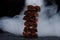 Porous chocolate in stack on a black background closeup. Pieces of milk chocolate, lined up in a tower, shrouded in smoke.