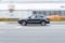 Porsche Macan Turbo car moving on the street. Gray luxury SUV in motion, side view. Car driving on freeway with motion blur