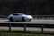 Porsche panamera white rides on the road. Against a background of blurred trees