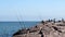 PORT ARANSAS, TX - 2 FEB 2020: Fishing Rods and Reels propped at the South Jetty as a nearby fisherman casts his bait and line