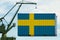 Port crane holds a container with the flag of Sweden, the concept of shipping from a country around the world by sea, distribution