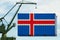 Port crane holds a container with iceland flag, concept of shipping from a country around the world by sea, distribution of goods