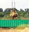 The port crane makes loading of wood chips into the freight wagons of the train, close-up, ladle, grab