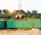 The port crane makes loading of wood chips into the freight wagons of the train, close-up, ladle, grab