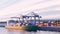 Port cranes loading containers on a cargo ship at the port. Tilt-shift effect. Digital 3D render, low poly