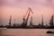 Port docks at sunset. Unloading ships on background of evening sky. Sea port and unloading of cargo containers. Silhouette of dock