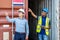 Port manager and a colleague tracking inventory while standing point to position loading Containers box from Cargo freight ship