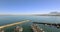 Port, ocean and boat with drone for sea transport, travel and tourism with blue sky background and beach on the horizon