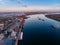 Port river cranes loading ships on barges delivery, sunset