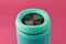 Portable audio speaker subwoofer, close-up. Turquoise Wireless speaker on a pink background