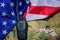 Portable black walkie-talkie on American flag and camouflage military background