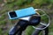 A portable charger charges a smartphone on the background of a bicycle and nature. Power Bank on a journey to charge