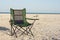 A portable foldable solar panel hangs on a travel chair. Tourist camping on the seashore