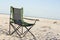 A portable foldable solar panel hangs on a travel chair. Tourist camping on the seashore