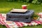 portable grill on picnic blanket, surrounded by greenery