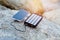 Portable powered solar usb charges the phone and is located on a rock on the beach. Alternative energy. Eco.