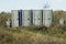 Portable public toilets in the middle of a field on a sunny winter day