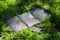 Portable solar battery and mobile phone on green grass. Charging electronic gadgets on a hike, during outdoor recreation.