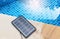 Portable solar cell panel on swimming pool background, clean energy concept