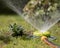 Portable sprinkler sprays water on the lawn ang gras