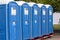 Portable street WC toilet cabins in a park. A line of chemical toilets for a festival, against a forest background