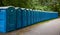 Portable WC cabins in the park. A line of chemical toilets for a festival, against a forest