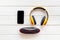 Portable wireless speakers, phone and headphones for music listening on white wooden background top view