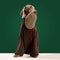 Portait of clever dog Weimaraner wearing sweater holding owner& x27;s hat in mouth over green studio background