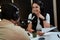 Portait of happy female radio host smiling, listening to male guest, presenter and holding a script paper while