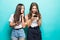 Portait of two mixed race women browsing internet or using mobile phones over blue background