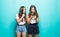 Portait of two mixed race women browsing internet or using mobile phones over blue background