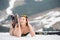 Portait of woman skier is relaxing on the snowy slope in the mountains. Wearing swimsuit, boots and sunglasses