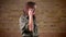 Portait of young beautiful brown-headed woman talking on cellphone and laughing on bricken wall background.