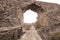 Portal in the medieval castle wall. The wall built of rocks and bricks with a window in the middle.