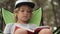 Portarit of child reading a book on pine wood background.