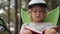 Portarit of child reading a book on pine wood background.