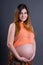 portarit of happy young beautiful pregnant woman posing over grey