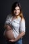 Portarit of young beautiful pregnant woman posing over grey
