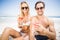 Portarit of young couple in sunglasses having cocktail on the beach