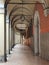 A portico in Bologna, Italy. A lamp hanging from the arched roof.