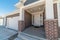 Portico with white front door adjacent to the garage door at the facade of house