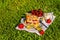Portion of cherry cake on a towel with strawberries on grass