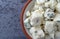 Portion of crumbled blue cheese on a in a small bowl atop a gray background top close view