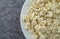 Portion of crumbled blue cheese on a white plate atop a gray background top close view