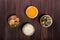 Portion cups of healthy sweet ingredients on dark wooden table, fried pumpkin seeds, grated parmesan cheese, honey, walnuts.