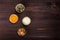 Portion cups of healthy sweet ingredients on dark wooden table, fried pumpkin seeds, grated parmesan cheese, honey, walnuts.