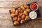 Portion Deep-fried chicken nuggets in coconut flakes served with ketchup and mayonnaise close-up on a slate board. Horizontal top