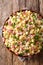 Portion of Ditalini pasta with green peas, ham and cheese closeup on a plate. vertical top view