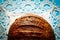 Portion of fresh bread with a round shape on a linen tablecloth, blue background